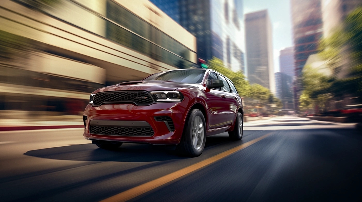 Dodge Durango GT 2025 rouge roulant en pleine ville sur une route dégagée.