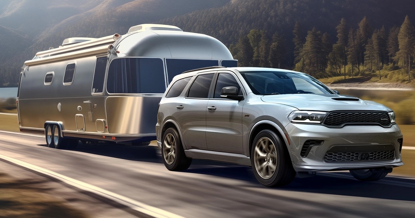 Dodge Durango 2025 gris remorquant une roulotte sur une route de campagne.