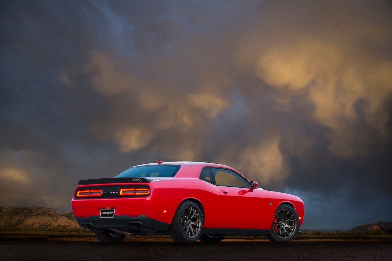 Vue 3/4 arrière du Dodge Challenger SRT 2017 sous un ciel nuageux et orangé.