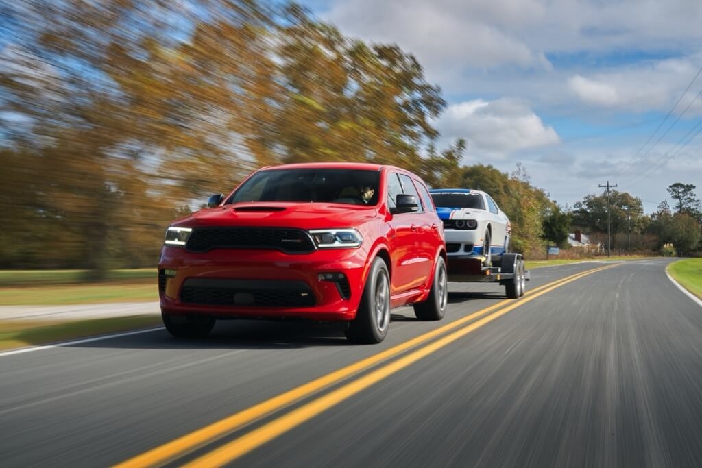 Vue 3/4 avant du VUS Dodge Durango 2021 remorquant un Dodge Challenger sur la route.